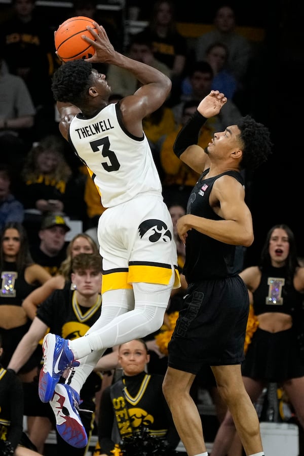 Iowa guard Drew Thelwell, left, shoots over Michigan State guard Jaden Akins, right, during the first half of an NCAA college basketball game, Thursday, March 6, 2025, in Iowa City, Iowa. (AP Photo/Charlie Neibergall)