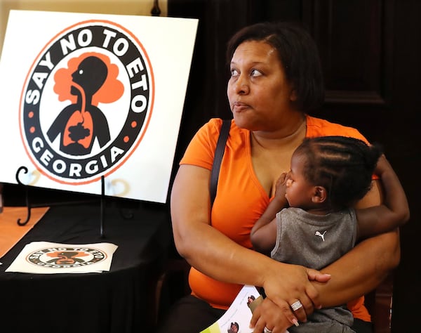 Covington resident Denise Williams holds her 1-year-old godson Davion Petty while attending the Town Hall presentation on ethylene oxide gas from the nearby Becton Dickinson plant. Curtis Compton/ccompton@ajc.com