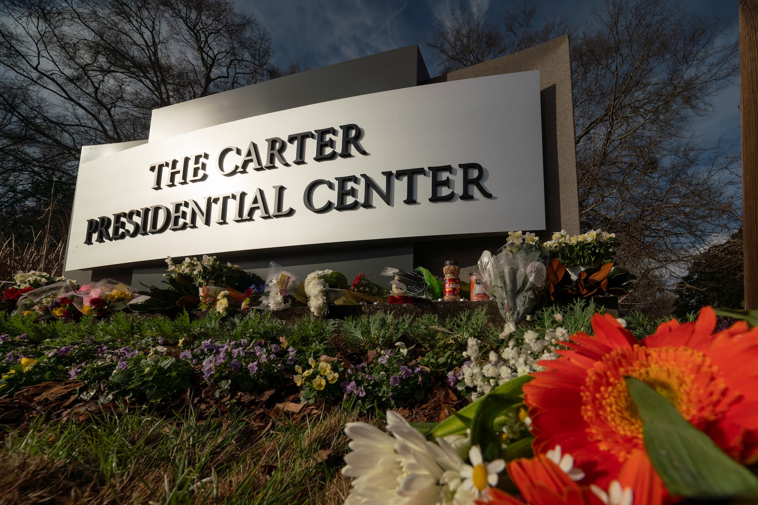 Flowers, candles and peanuts line the sign at The Carter Presidential Center in Atlanta,Georgia after the death of the former president.