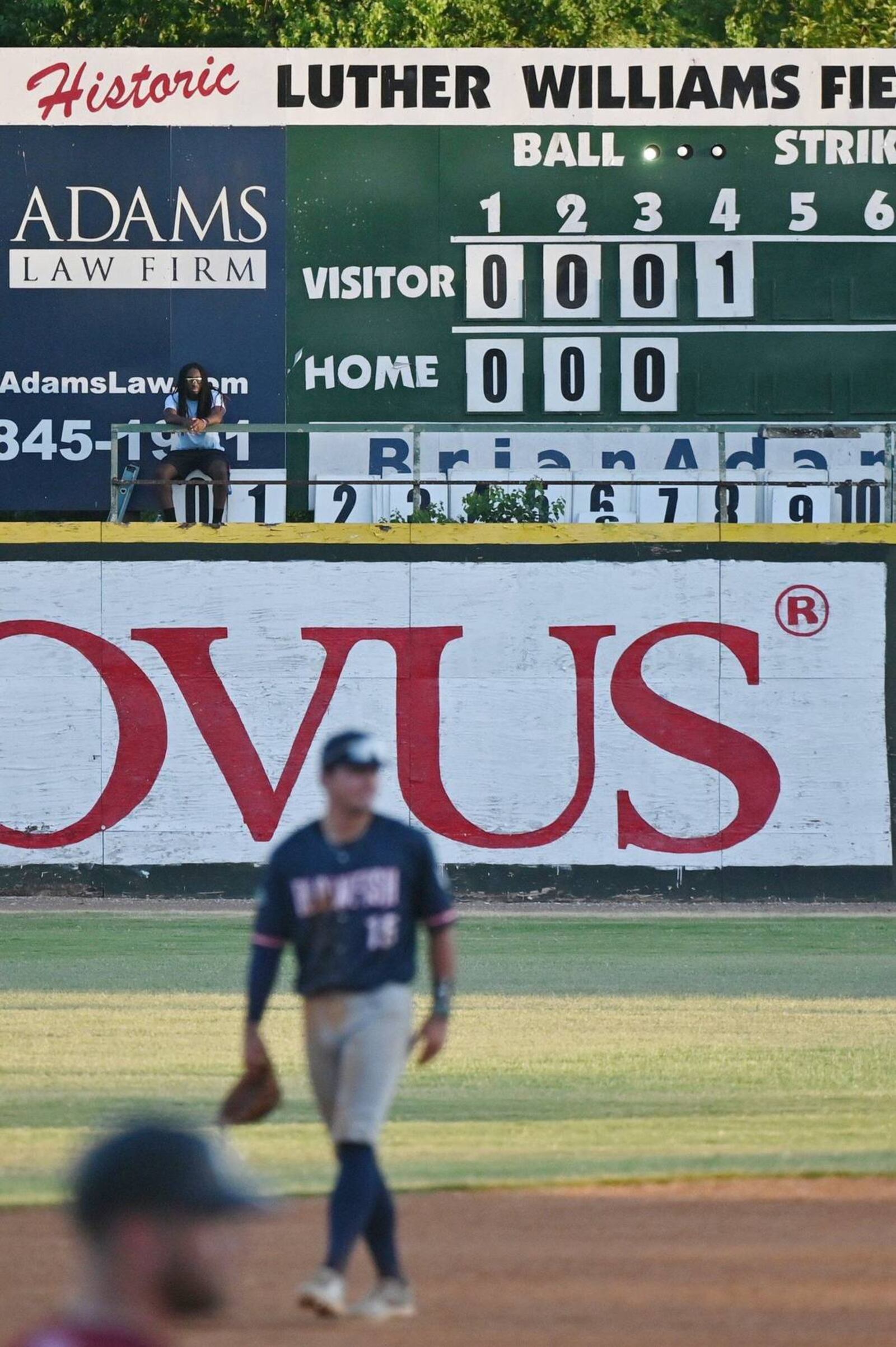 Luther Williams Field scoreboard operator Christian Kendrick sits up on the elevated manual scoreboard during the Macon Bacon game against Catawba Valley Stars on Tuesday, June 25, 2024, in Macon, Georgia. Luther Williams Field saw extensive renovations in 2018, but the scoreboard remains the original from the park’s opening in 1929. (Photo Courtesy of Katie Tucker/The Telegraph)