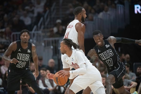 Cleveland Cavaliers' Darius Garland, center drives against Brooklyn Nets' Dorian Finney-Smith (28) and Brooklyn Nets' Dennis Schroder (17) as Evan Mobley (4) blocks during the first half of an NBA basketball game in Cleveland, Saturday, Nov. 9, 2024. (AP Photo/Phil Long)