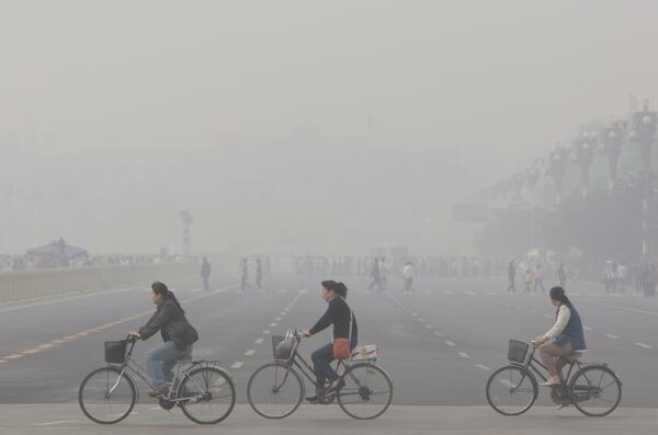 Chinese women cycling through smog and pollution over Beijing's Tiananmen Square in 2008. (AP Photo/Oded Balilty, File)