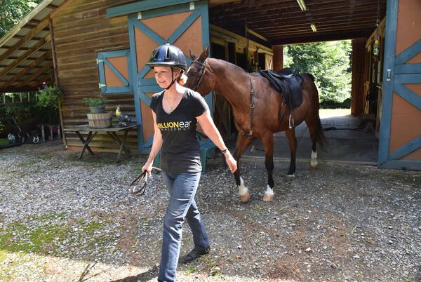 Robin Chisolm-Seymour prepares before she rides on her horse Jabez recently. As an equestrian, she won championships, but when she started losing her hearing, it affected her balance, and she had to make adjustments to return to horseback riding. HYOSUB SHIN / HSHIN@AJC.COM