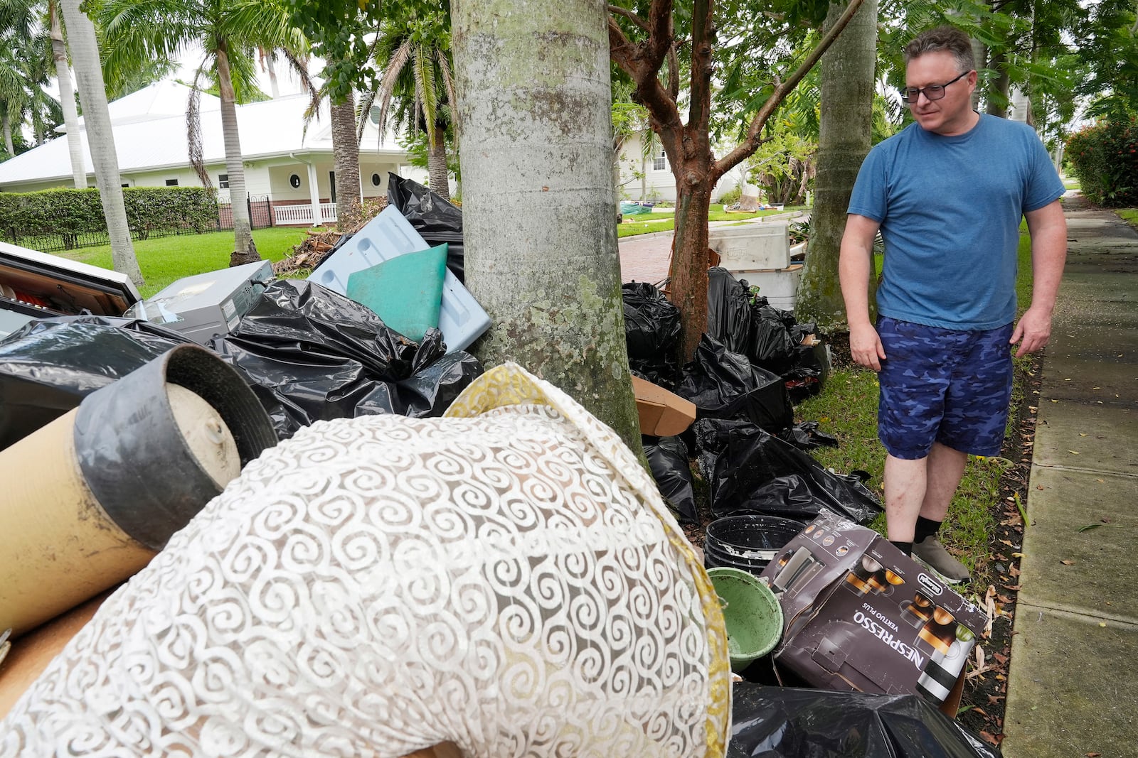 Scott Joyner looks at damaged items he removed from his garage following flooding caused by Hurricane Helene, Tuesday, Oct. 8, 2024, in Punta Gorda, Fla., as residents of of the historic neighborhood are now bracing for possible storm surge from Hurricane Milton. (AP Photo/Marta Lavandier)