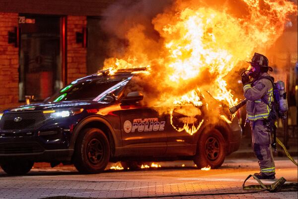 Atlanta firefighters prepare to extinguish a police car that was set afire during a Forest Defenders protest Saturday in Atlanta. (Steve Schaefer/The Atlanta Journal-Constitution/TNS)