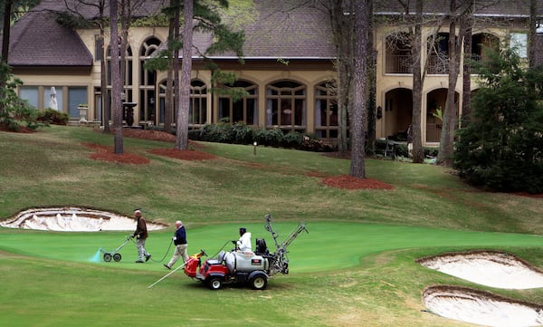 Grounds crews work on a green as a huge homes sits nearby on the golf course at the Country Club of the South in Johns Creek. AJC FILE PHOTO