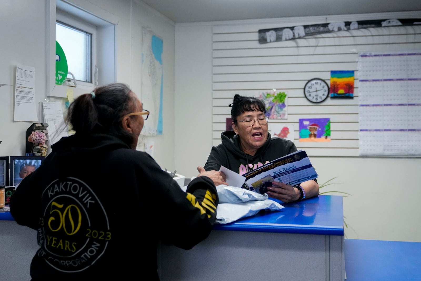 Postmaster Angel Akootchook, the village's only full-time postal employee, hands a stack of mail to a resident in Kaktovik, Alaska, Wednesday, Oct. 16, 2024. (AP Photo/Lindsey Wasson)