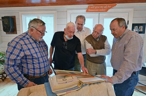 Former Tom's Foods employees (from left) Johnny Johnson, Don Tillery, Jack Warden, Ben Smith, and Jernigan Gresham share old photographs from Tom's Foods at the Midland home of Warden, a former Tom's general manager, on Friday, Feb. 26, 2021. Campbell Soup Co. announced plans to close its Columbus manufacturing facility by spring 2022. The plant produces candy, crackers, cookies, nuts and bars. It was once known as Tom's Foods. (Hyosub Shin / Hyosub.Shin@ajc.com)