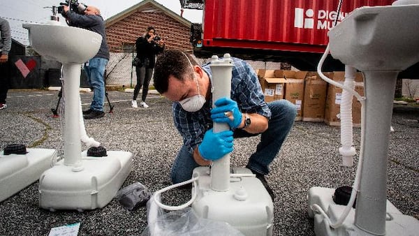 A volunteer worker assembles a portable wash station on Thursday, March 19, 2020 in College Park, Georgia. The wash stations were distributed by rapper Lecrae and volunteers with Love Beyond Walls throughout Atlanta in areas with a high density of homeless persons. (AP Photo/ Ron Harris)