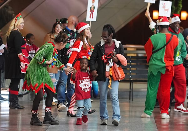 Flight attendant Dre Zulaica, front left, of San Francisco, greets a participant and her guardian during the United Airlines annual "fantasy flight" to a fictional North Pole at Denver International Airport, Saturday, Dec. 14, 2024, in Denver. (AP Photo/David Zalubowski)