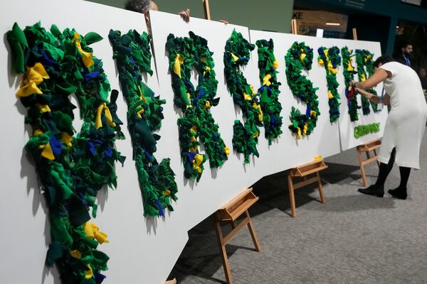 An activist works on a display that reads in Portuguese persistir, that translates to persist, during the COP29 U.N. Climate SuRafiq Maqbool Nov. 22, 2024, in Baku, Azerbaijan. (AP Photo/Rafiq Maqbool)