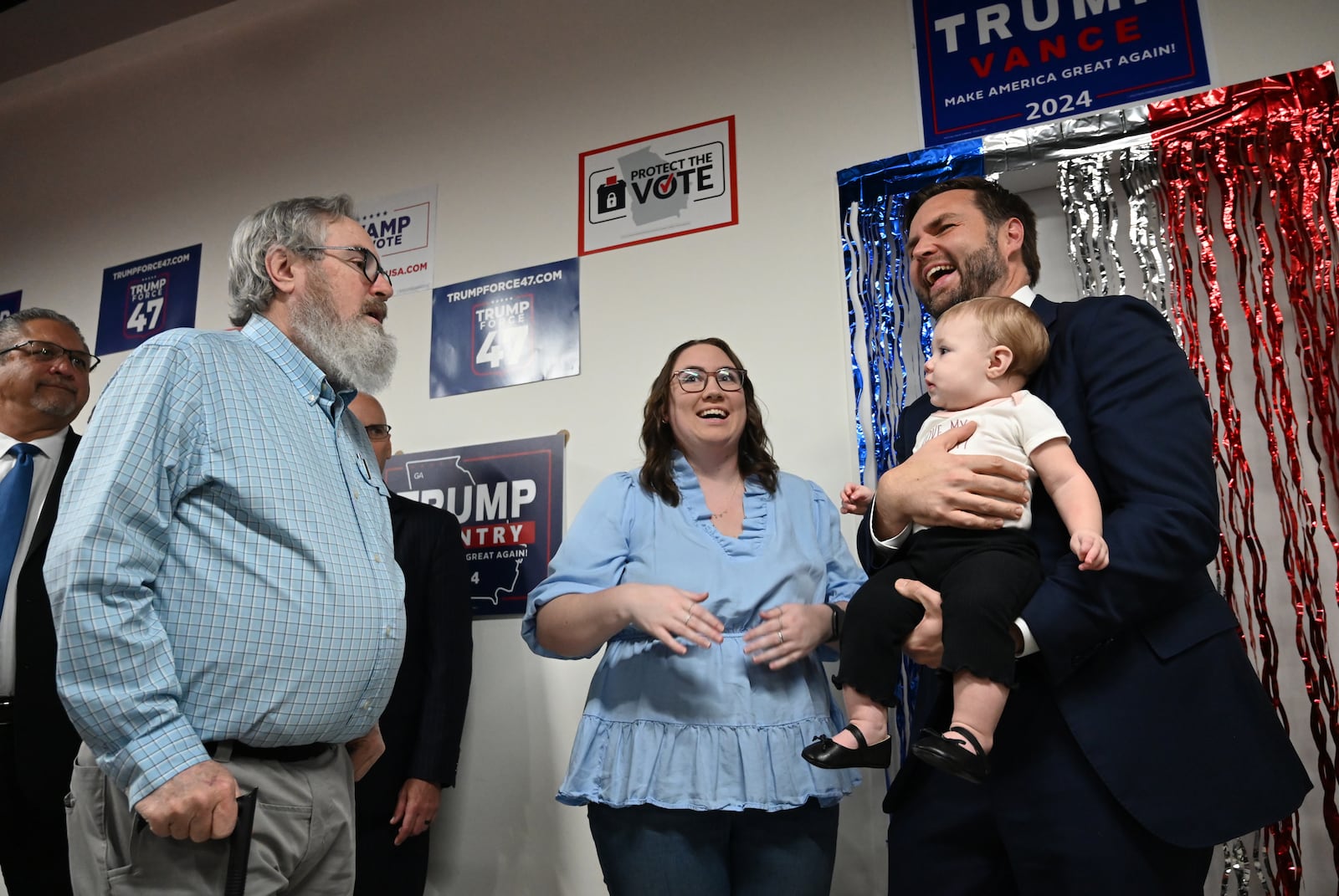 Republican vice presidential nominee JD Vance holds 10-month-old Emmalynn as her grandfather David Lowry (left) and mother Daelen Lowry (center) react as JD Vance visits Trump Force 47 - Gwinnett Field Office, Friday, October 11, 2024, in Lawrenceville. (Hyosub Shin / AJC)