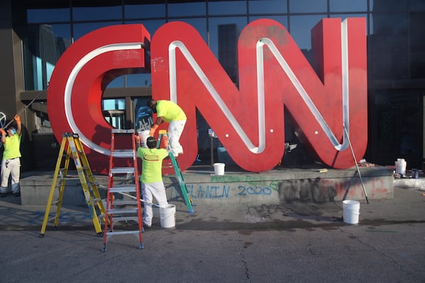 Workers clean up the CNN sign on Saturday morning. 