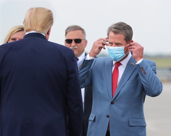 Gov. Brian Kemp adjusts his mask Wednesday as he greets President Donald Trump during his visit to Georgia to talk about easing the environmental review process to speed up the construction of infrastructure.  Curtis Compton ccompton@ajc.com