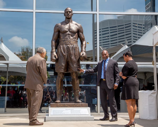 Legendary boxer Evander Holyfield, Mayor of Atlanta Keisha Lance Bottoms (right), and Rob Pitts, chairman of the Fulton County Board of Commissioners, (left) admire a bronze statue in Holyfield's likeness at State Farm Arena in Atlanta. STEVE SCHAEFER FOR THE ATLANTA JOURNAL-CONSTITUTION