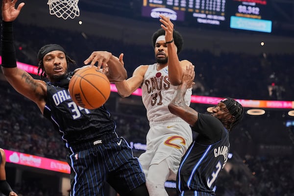 Orlando Magic center Wendell Carter Jr. (34), Cleveland Cavaliers center Jarrett Allen (31) and guard Kentavious Caldwell-Pope (3) reach for a rebound in the first half of an NBA basketball game Sunday, March 16, 2025, in Cleveland. (AP Photo/Sue Ogrocki)