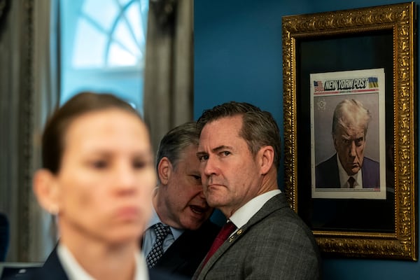 Mike Walz, the national security adviser, stands next to a framed copy of the New York Post front page bearing the Fulton County Jail booking photo of President Donald Trump.