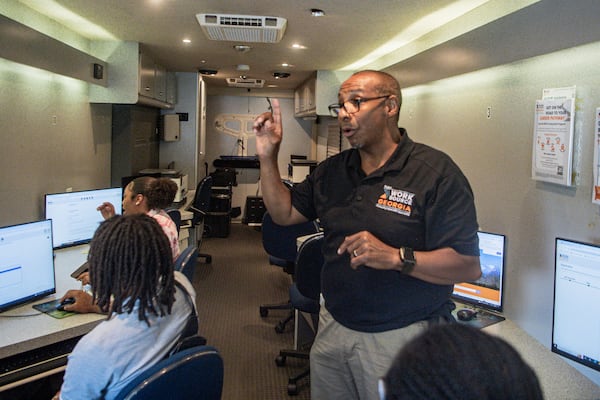 Scott Jackson, (right), business service consultant for WorkSource Fulton helps job seekers with their application in a mobile carer center at a job fair hosted by Goodwill Career Center in Atlanta on Tuesday, July 9, 2024.  (Ziyu Julian Zhu / AJC)