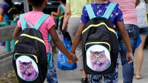  In this file photo, children hold hands as they walk with their new book bags, in Miami. No more staying up late during the week. Farewell to sleeping in. And, hello homework! (AP Photo/Lynne Sladky, File)