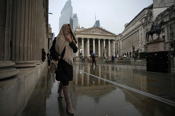 A woman walks past the Bank of England, at the financial district, in London, Thursday, March 13, 2025. (AP Photo/Kin Cheung)