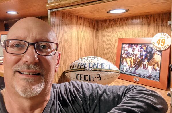 Former Georgia Tech football player Duane Wood in his Roswell home with the game ball he received for his role in the Yellow  Jackets' 3-3 tie with No. 1 Notre Dame on Nov. 8, 1980, along with a photo from the game.