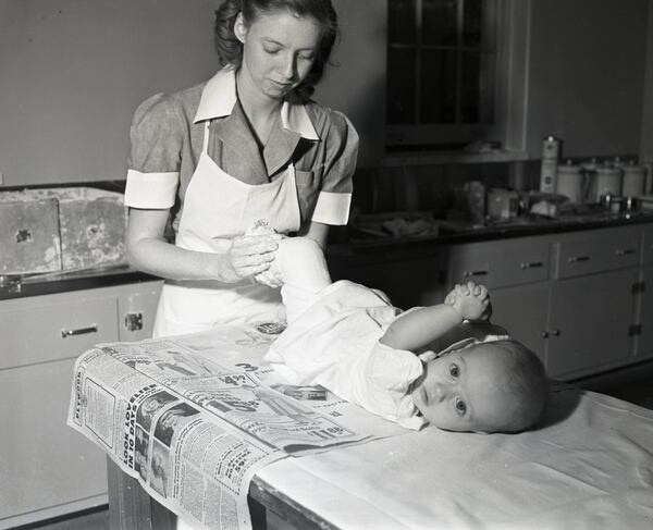 Nurse putting a cast on an infant with polio, circa 1940s. AJC file.