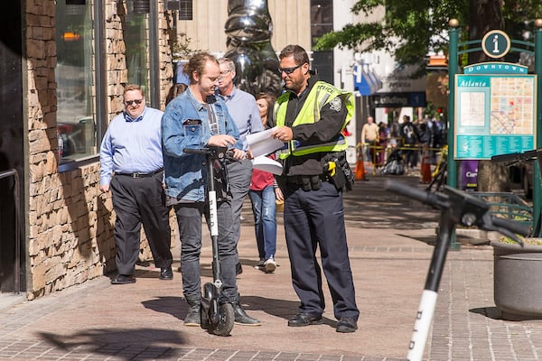 10/17/2019 -- Atlanta, Georgia -- Atlanta Police Officer C. Walden stops a scooter rider on the sidewalk along Peachtree Street NE during his foot beat patrol, Thursday, October 17, 2019. Foot beat Atlanta police officers carry informational handouts that advise ride-share scooter operators on the laws of riding in the city. Officers will give warnings to riders and issue citations to repeat offenders.  (Alyssa Pointer/Atlanta Journal Constitution)