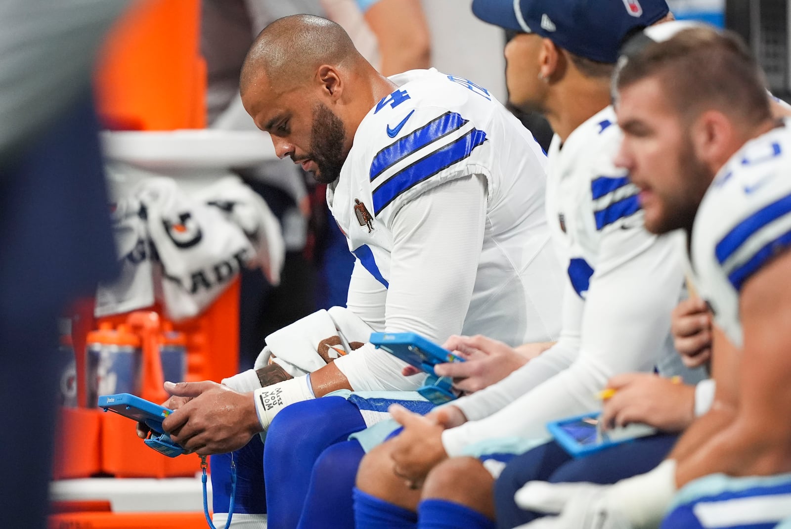 Dallas Cowboys quarterback Dak Prescott (4) reads a tablet on the bench during the first half of an NFL football game against the Atlanta Falcons, Sunday, Nov. 3, 2024, in Atlanta. (AP Photo/ Brynn Anderson)