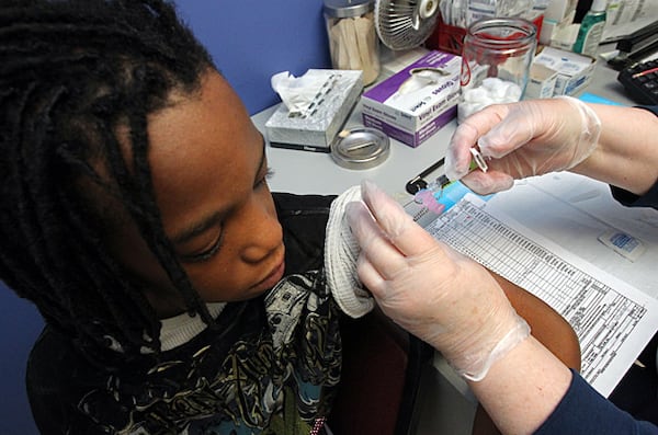 Fay Bishop gives Remondo Swinney, 12, a TDaP shot at the T.O. Vinson Health Center in Decatur.