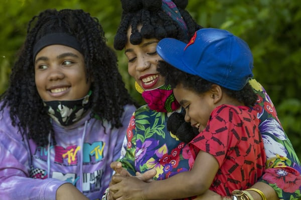 Inas Mahdi (center) shares a laugh with her children Kafele Mahdi-Minnifield (right) and Suhana Mahdi-Minnifleid (left) during a pull-up portrait session with photographer Melissa Alexander in Atlanta’s West End community, Friday, May 1, 2020. Inas had been photographed by Alexander before but wanted to commemorate this historical time by being photographed with her children. “We’re living through history,” Inas said, “You can see that we’re trying to still find joy.” ALYSSA POINTER/ALYSSA.POINTER@AJC.COM