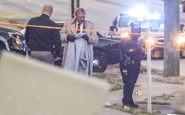 DeKalb County police Sgt. B. Danner (center) stands near a body during a homicide investigation Wednesday morning at the Austin Plaza on Glenwood Road.