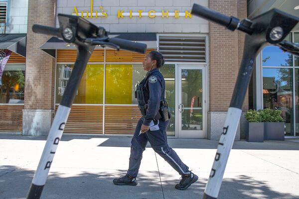 Ride-share scooters line the sidewalk of Peachtree Street Northeast as Atlanta Zone 5 Police Officer Ayesha Abdul-Hakeem patrols on her foot beat in Atlanta's Midtown community, Thursday, Oct. 17, 2019.   (Alyssa Pointer/Atlanta Journal Constitution)