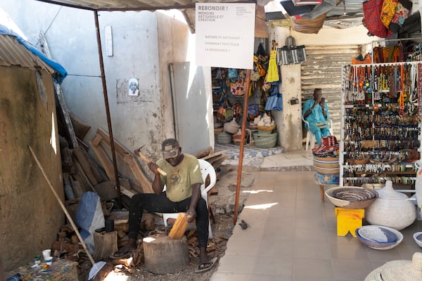 Woodcarver Papis Kanté sculpts a wooden hippopotamus to be exhibited in the "Rebondir" exhibition as part of the Dakar 2024 Biennial Off in Dakar, Senegal, Thursday, Nov. 28, 2024. (AP Photo/Sylvain Cherkaoui)