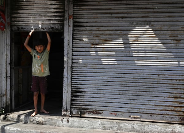 A boy looks out from the closed shutter of a shop a day after communal clashes sparked by protests demanding removal of the tomb of 17th-century Muslim Mughal ruler Aurangzeb in Nagpur, India, Tuesday, March 18, 2025. (AP Photo)