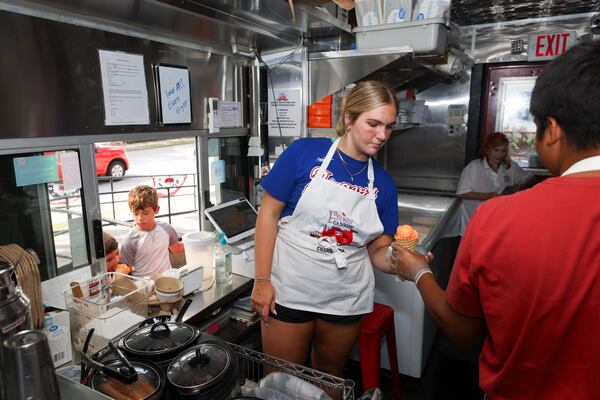 Caitlyn Kachmar, 17, prepares to serve an orange sherbet cone to a young customer at the Frosty Caboose. Caitlyn is the youngest child of shop owner Pam Kachmar. (Jason Getz/jason.getz@ajc.com)
