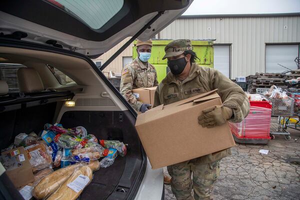 U.S. Army National Guardsman Nukonda White, front, and Sergeant John Pamphile helped load groceries at the Hearts to Nourish Hope food pantry in Riverdale last month. (Alyssa Pointer / Alyssa.Pointer@ajc.com)