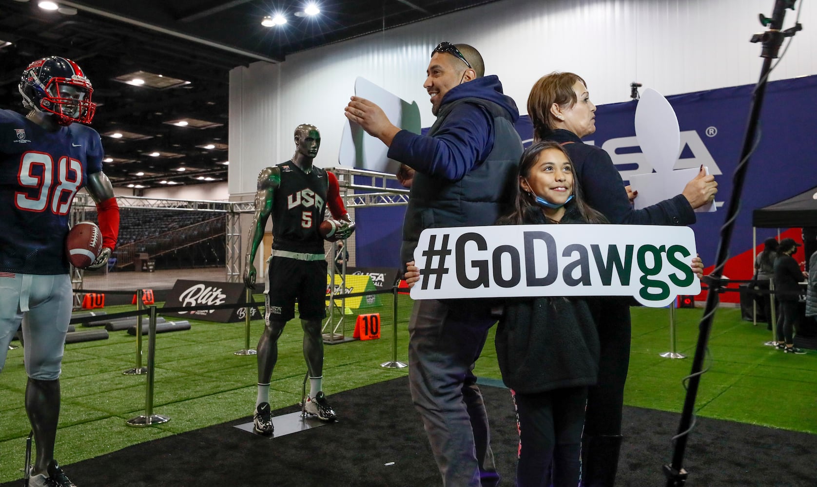 Anthony Bays  (from left), from Indianapolis, with his daughter, Erika, 9, and her mom, Maria, root for Georgia in the 3d photo booth.  Anthony said he was tired of Alabama winning and wanted Georgia to wim.   They were at Fan Central in the Indiana Convention Center at the 2022 College Football Playoff National Championship  between the Georgia Bulldogs and the Alabama Crimson Tide at Lucas Oil Stadium in Indianapolis on Saturday, January 8, 2022.   Bob Andres / robert.andres@ajc.com