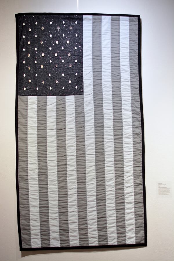 "Capital Gains" quilted black and gray American flag with cowrie shells for stars. Accompanied by an excerpt from David Walker's Appeal (1829), by Jerushia Graham.
Courtesy of Caroline Giddis