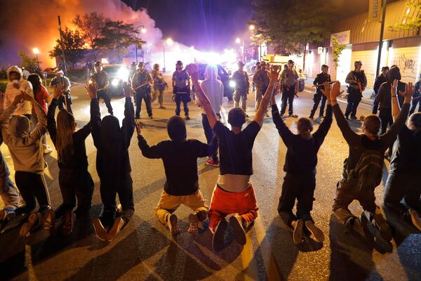 Demonstrators kneel before police Saturday in Minneapolis. Protests continued following the death of George Floyd.