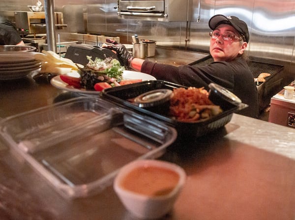 Marlow's Tavern cook Ana Murcia works on both meals and to-go orders during their lunch rush on Friday. John Metz, co-owner of the Marlow’s Tavern chain, says that the shift of many restaurants to takeout has meant soaring demand for items like to-go boxes, doubling or tripling the cost of those supplies. “That is a big hit to the bottom line,” Metz said. (Steve Schaefer for The Atlanta Journal-Constitution)