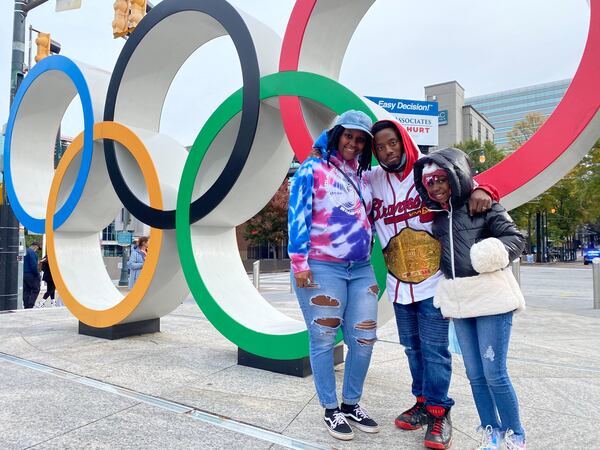 Jasmine Carter, Tyrae Carter and their 8-year-old daughter Lyndon pose in front of the Olympic rings at Centennial Olympic Park on Nov. 5, 2021. Ben Brasch/AJC