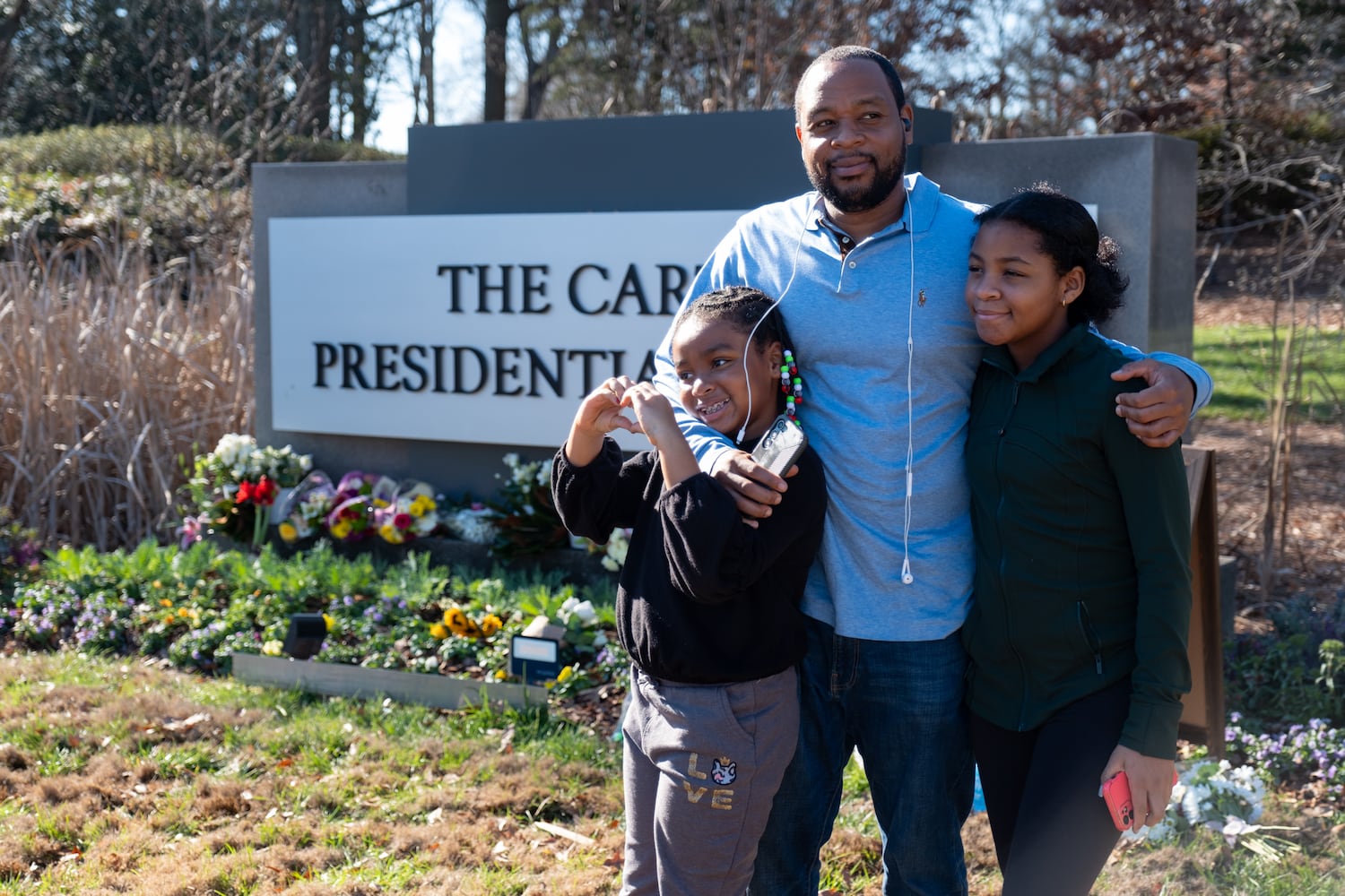 Coty Durant brought his daughters Layla, 8, left, and Harper, 12, to pay their respects to former President Jimmy Carter at the Carter Center in Atlanta on Monday, Dec. 30, 2024. Durant is a history buff and wanted to use the moment to teach his children.  Ben Gray for the Atlanta Journal-Constitution