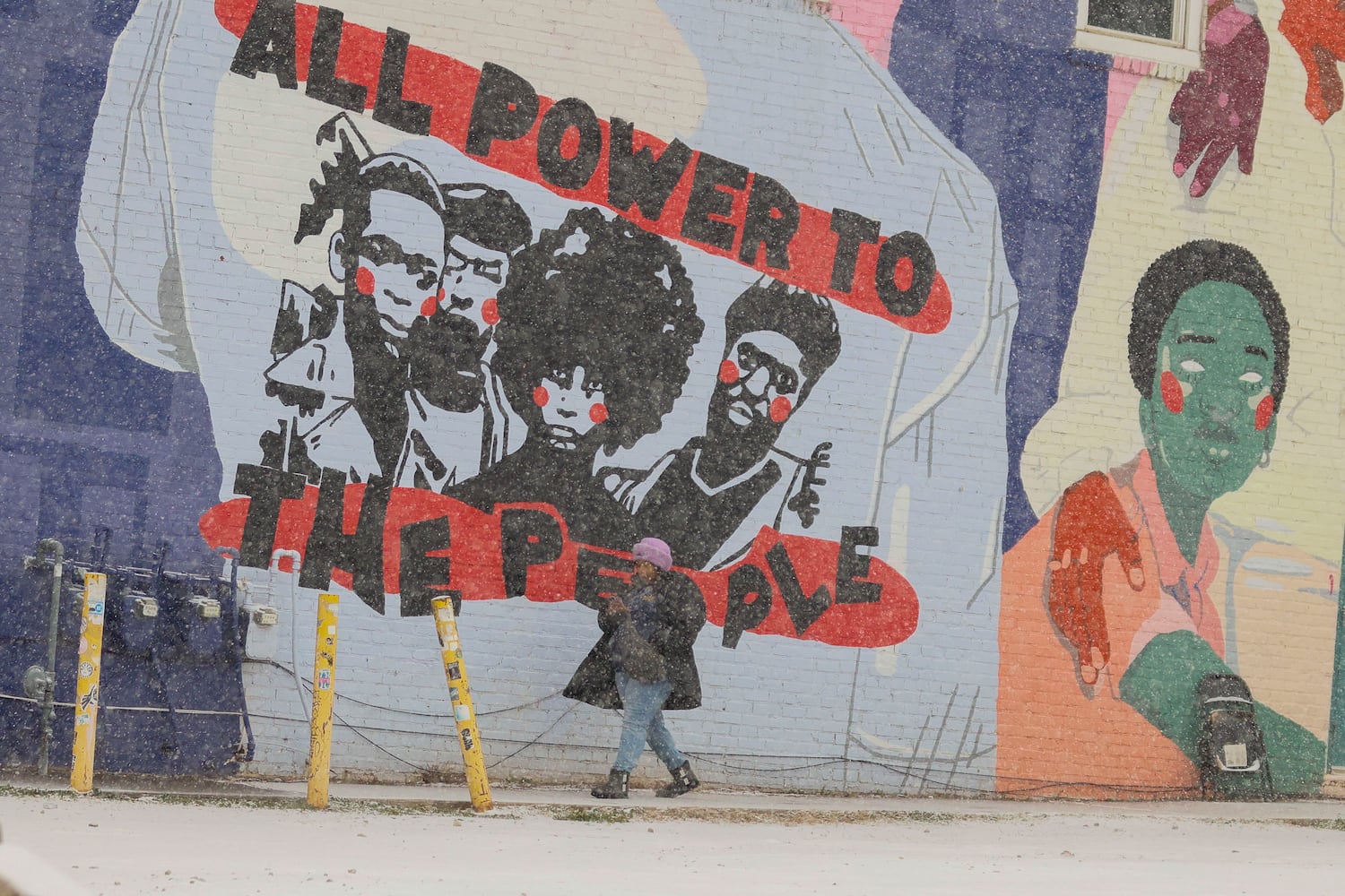 A person walks in front of a mural near Edgewood Ave. in the afternoon on Tuesday, January 21, 2025, as snow starts covering the street.