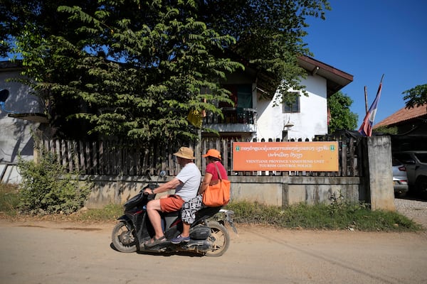 Tourists ride on a motorbike near the tourism control police station in Vang Vieng, Laos, Friday, Nov. 22, 2024. (AP Photo/Anupam Nath)