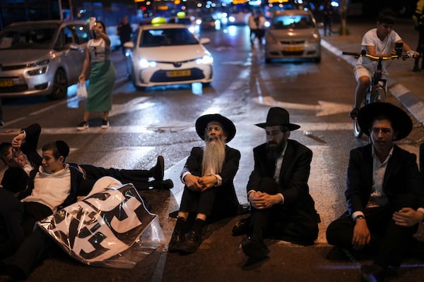 Ultra-Orthodox Jewish men block a road during a protest against army recruitment in Bnei Brak, near Tel Aviv, Israel, Sunday, Nov. 17, 2024. (AP Photo/Francisco Seco)