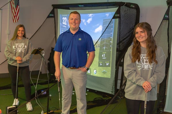 (From left) Haven Blank, coach Travis Farmer and Olivia Kirkland enjoy the new indoor practice facility at Harrison High School. (Hunter Cook photo)