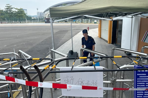 A security guard looks at inside the barricaded entrance to the "Zhuhai People's Fitness Plaza" where a man rammed his car into people exercising at the sports center, in Zhuhai in southern China's Guangdong province on Wednesday, Nov. 13, 2024. Sign in white reads "Temporarily Closed". (AP Photo/Ng Han Guan)