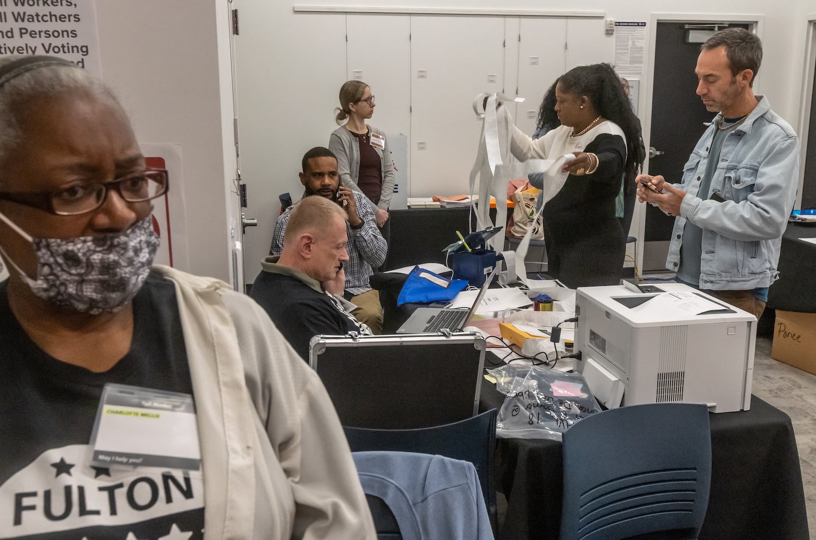 Poll worker Charlotte Mellix, left, keeps an eye on things Tuesday as poll workers sort through material during early voting at the Joan P. Garner Library in Atlanta. (John Spink/AJC)