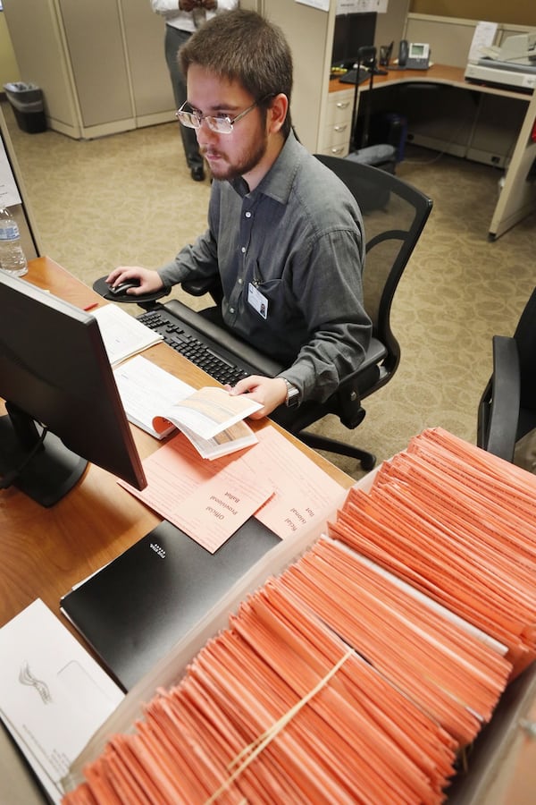 A day after voting concluded, David Laurencio and other registration specialists checked provisional ballots at the Fulton County Board of Registration and Elections. BOB ANDRES / BANDRES@AJC.COM