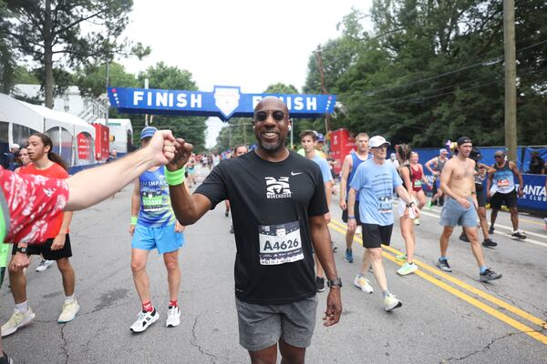 Sen. Raphael Warnock celebrates at the finish of the 54th running of the Atlanta Journal-Constitution Peachtree Road Race in Atlanta on Tuesday, July 4, 2023.   (Jason Getz / Jason.Getz@ajc.com)